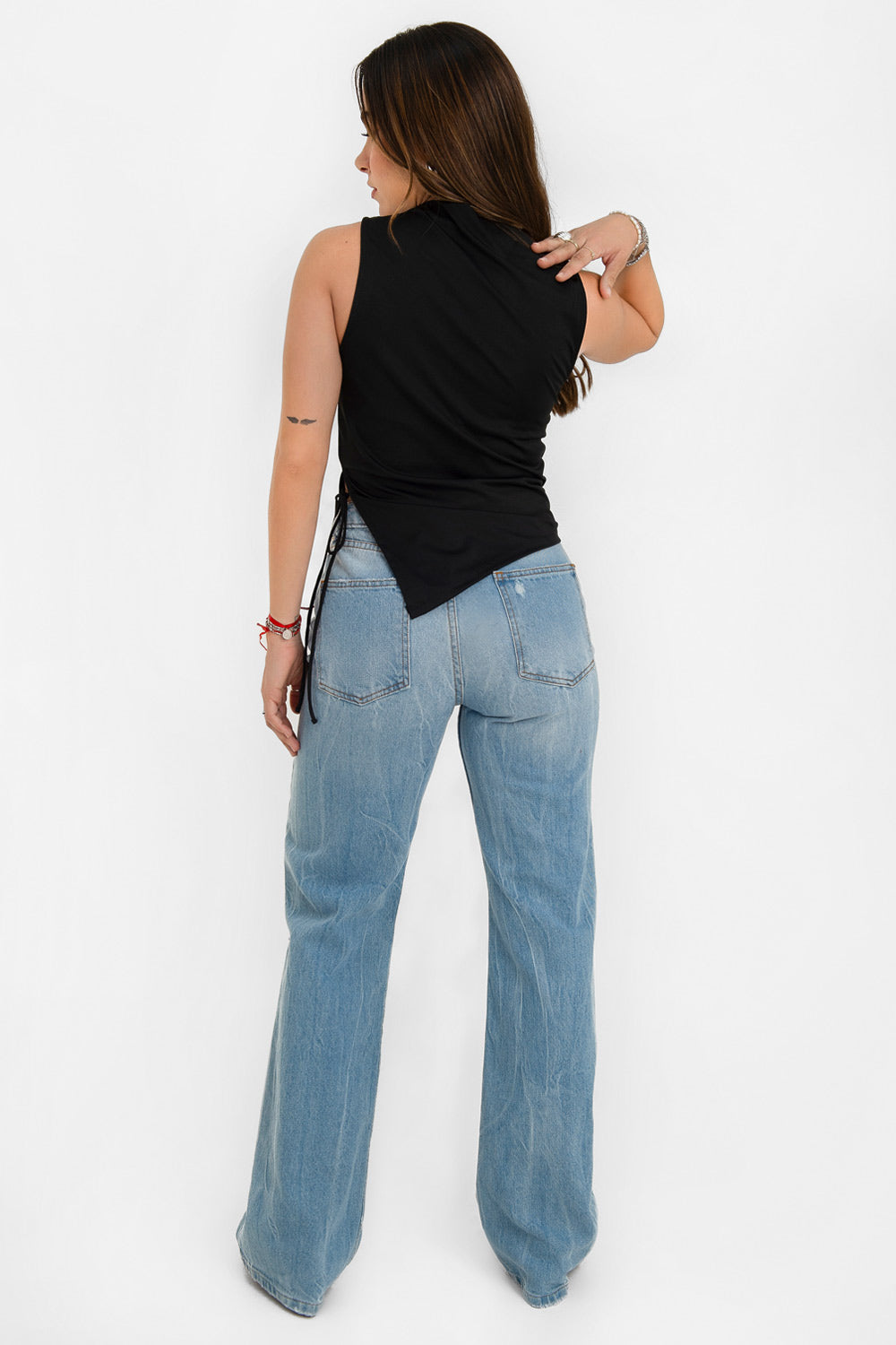 Top asimétrico de fit recto, cuello barco, sin mangas, bajo asimétrico diagonal con abertura lateral y lazo amarrable decorativo.