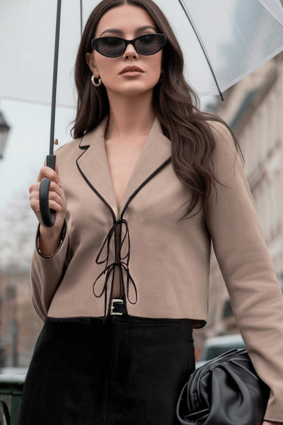 Top blazer corto de fit fluido, manga larga, escote v con solapa y cierre frontal con lazos amarrables. Detalle de ribete decorativo en contraste.