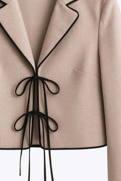 Top blazer corto de fit fluido, manga larga, escote v con solapa y cierre frontal con lazos amarrables. Detalle de ribete decorativo en contraste.