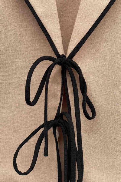 Top blazer corto de fit fluido, manga larga, escote v con solapa y cierre frontal con lazos amarrables. Detalle de ribete decorativo en contraste.