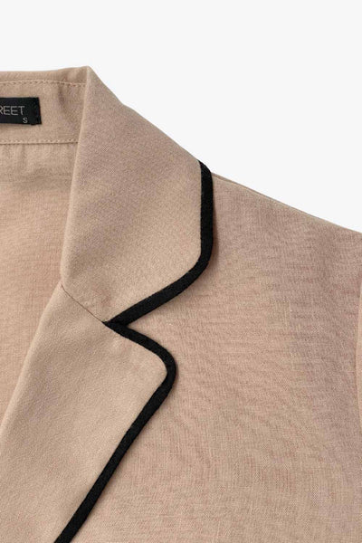 Top blazer corto de fit fluido, manga larga, escote v con solapa y cierre frontal con lazos amarrables. Detalle de ribete decorativo en contraste.