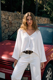 Blusa tipo capa de fit fluido, manga larga amplia, cuello v y bajo asimétrico. Detalle de textura en tejido.