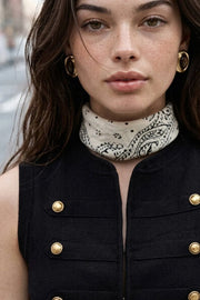 Top tipo chaleco corto de fit ajustado, cuello mao, sin mangas, detalle frontal con botones decorativos en contraste y bajo curveado frontal. Cierre frontal con broches ocultos.
