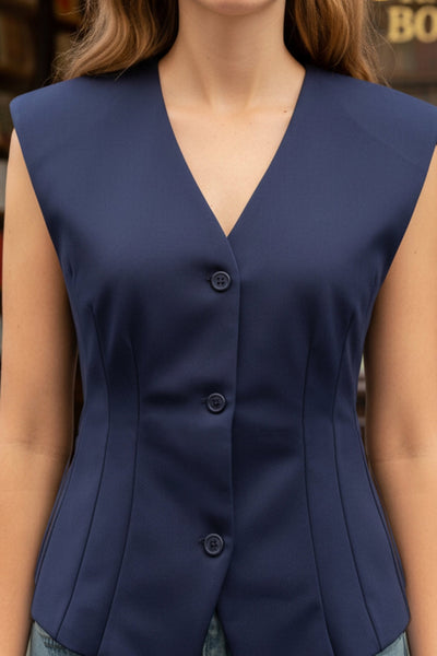 Chaleco de fit ajustado, cuello v, con hombreras y cierre frontal con hilera de botones. Detalle de abertura frontal en bajo.