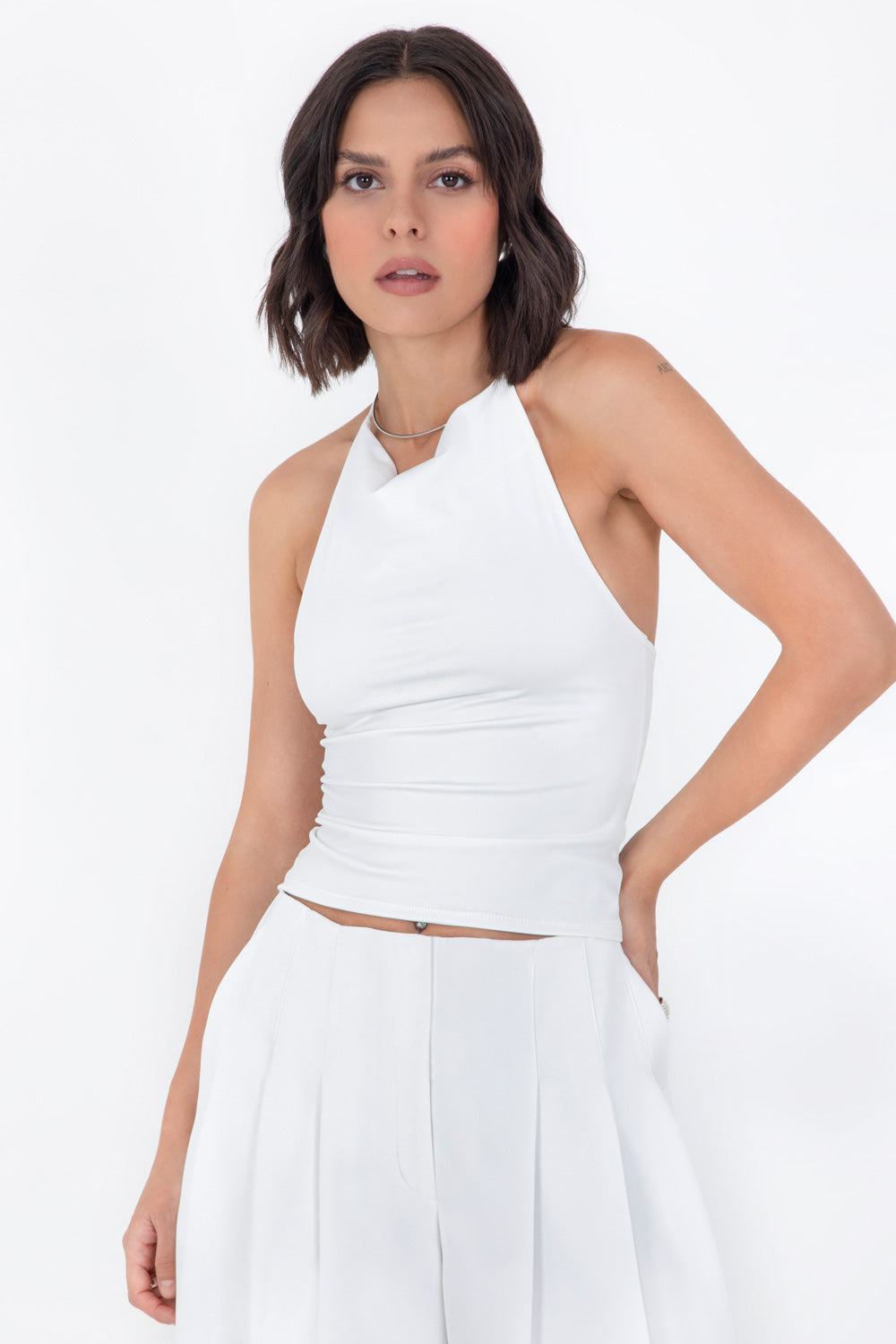 Top corto de cuello halter fluido, sin mangas, fit ajustado y escote en espalda.