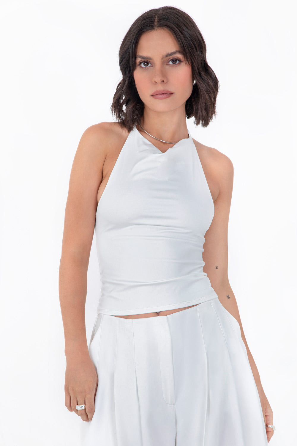 Top corto de cuello halter fluido, sin mangas, fit ajustado y escote en espalda.