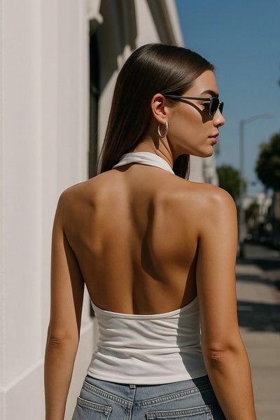 Top corto ajustado de cuello halter con escote fluido, sin mangas, escote en espalda, cierre posterior con botón y ojal.