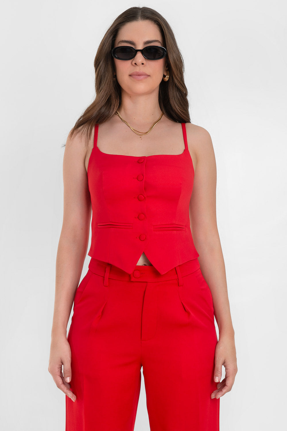 Top corto de fit ajustado, pinzas frontales, escote recto, tirantes delgados, vivos decorativos y cierre frontal con hilera de botones forrados. Detalle bajo v frontal.