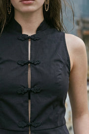 Top corto de fit ajustado, sin mangas, cuello mao, cierre frontal con botones y peplum con olanes en bajo.