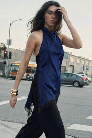 Blusa halter satinada de fit fluido, cuello halter fluido, sin mangas, bajo asimétrico con abertura lateral y encaje decorativo en contraste. Detalle de escote fluido en espalda, cierre posterior con botón y ojal.