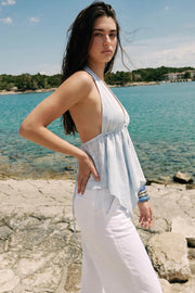 Top halter con lazo amarrable posterior, escote con plisados frontales, bajo asimétrico y jareta ajustable en espalda.