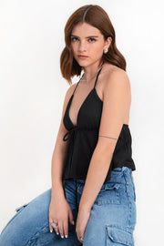 Top corto halter de escote v con lazo amarrable frontal, rib elástico en espalda, tirantes halter con lazo amarrable posterior y abertura frontal en bajo. Detalle de peplum olanes y textura en tejido.
