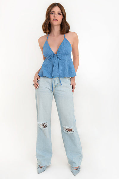 Top corto halter de escote v con lazo amarrable frontal, rib elástico en espalda, tirantes halter con lazo amarrable posterior y abertura frontal en bajo. Detalle de peplum olanes y textura en tejido.