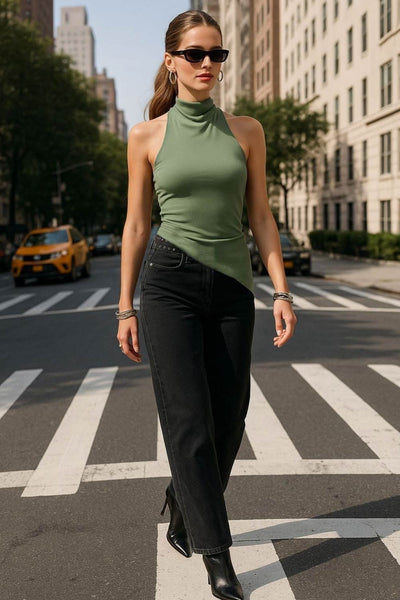 Top halter corto de fit ajustado, sin mangas, cuello halter fluido con plisados y escote en espalda. Detalle de bajo diagonal asimétrico.