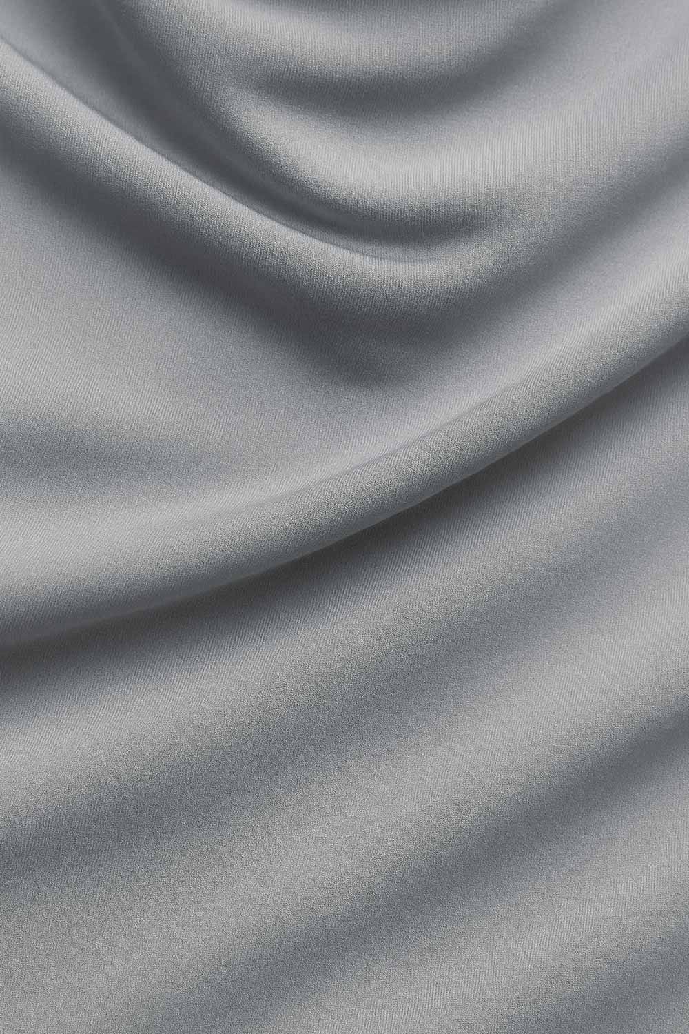 Top halter corto de fit ajustado, sin mangas, cuello halter fluido con plisados y escote en espalda. Detalle de bajo diagonal asimétrico.