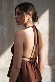 Top canalé de cuello halter con nudo amarrable posterior, escote v con plisados frontales, rib elástico en cintura y peplum olanes. Detalle de escote en espalda con lazo amarrable posterior.