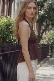 Top corto de cuello halter con lazo amarrable posterior, escote v con plisados, rib elástico en espalda y lazo amarrable en espalda. Detalle de peplum olanes en bajo y textura en tejido.