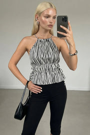 Top corto de estampado rayas, cuello halter con tirantes delgados, fit ajustado, rib con plisados en cintura y cuello. Detalle de jaretas ajustables en cintura, cierre posterior con botón y ojal.