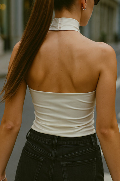 Top halter de fit ajustado, sin mangas, cuello alto, escote en espalda, cierre posterior con botón y ojal.