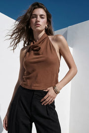 Top de cuello halter fluido, escote en espalda con lazo amarrable posterior, cierre con botón y ojal.