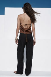 Top de cuello halter fluido, escote en espalda con lazo amarrable posterior, cierre con botón y ojal.