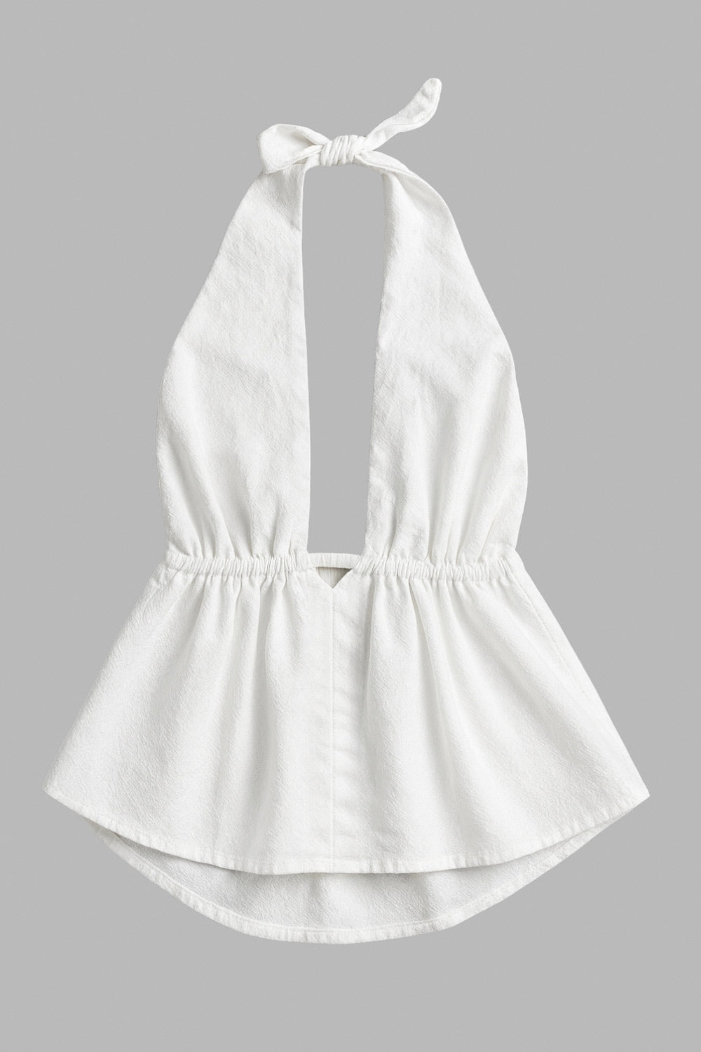 Top de cuello halter con nudo amarrable posterior, escote v con plisados frontales, rib elástico en cintura y peplum olanes. Detalle de escote en espalda con lazo amarrable posterior.