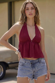Top corto de cuello halter con lazo amarrable posterior, escote v con plisados, rib elástico en espalda y lazo amarrable en espalda. Detalle de peplum olanes en bajo y textura en tejido.