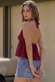 Top corto de cuello halter con lazo amarrable posterior, escote v con plisados, rib elástico en espalda y lazo amarrable en espalda. Detalle de peplum olanes en bajo y textura en tejido.