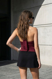 Top corto halter de fit ajustado, escote v cruzado con cortes, plisados decorativos y lazo amarrable posterior.