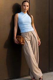 Top corto de fit ajustado, sin mangas, cuello mock con cruzado frontal y plisados decorativos.