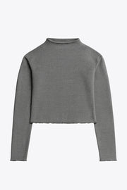 Top de manga larga con hombro caído, cuello mock seguido, fit recto, textura en tejido, detalle de rib en borde de bajo y puños.
