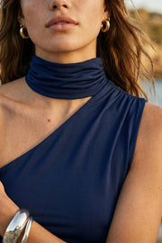 Top satinado asimétrico, de fit ajustado, detalles plisados laterales y en hombro, sin mangas, un hombro, escote diagonal y choker con plisados. Cierre posterior con botón y ojal.
