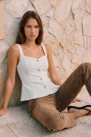 Top de fit ajustado, sin mangas, escote cuadrado, cortes frontales y peplum con olanes en bajo. Cierre frontal con hilera de botones en contraste.
