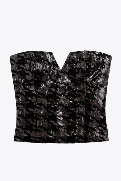 Crop top strapless de lentejuelas, estampado pata de gallo, escote corazón con detalle en v, cortes frontales y cierre posterior con cremallera visible en contraste.