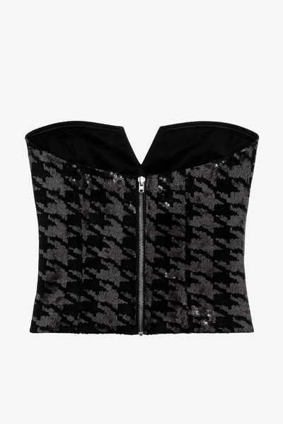 Crop top strapless de lentejuelas, estampado pata de gallo, escote corazón con detalle en v, cortes frontales y cierre posterior con cremallera visible en contraste.