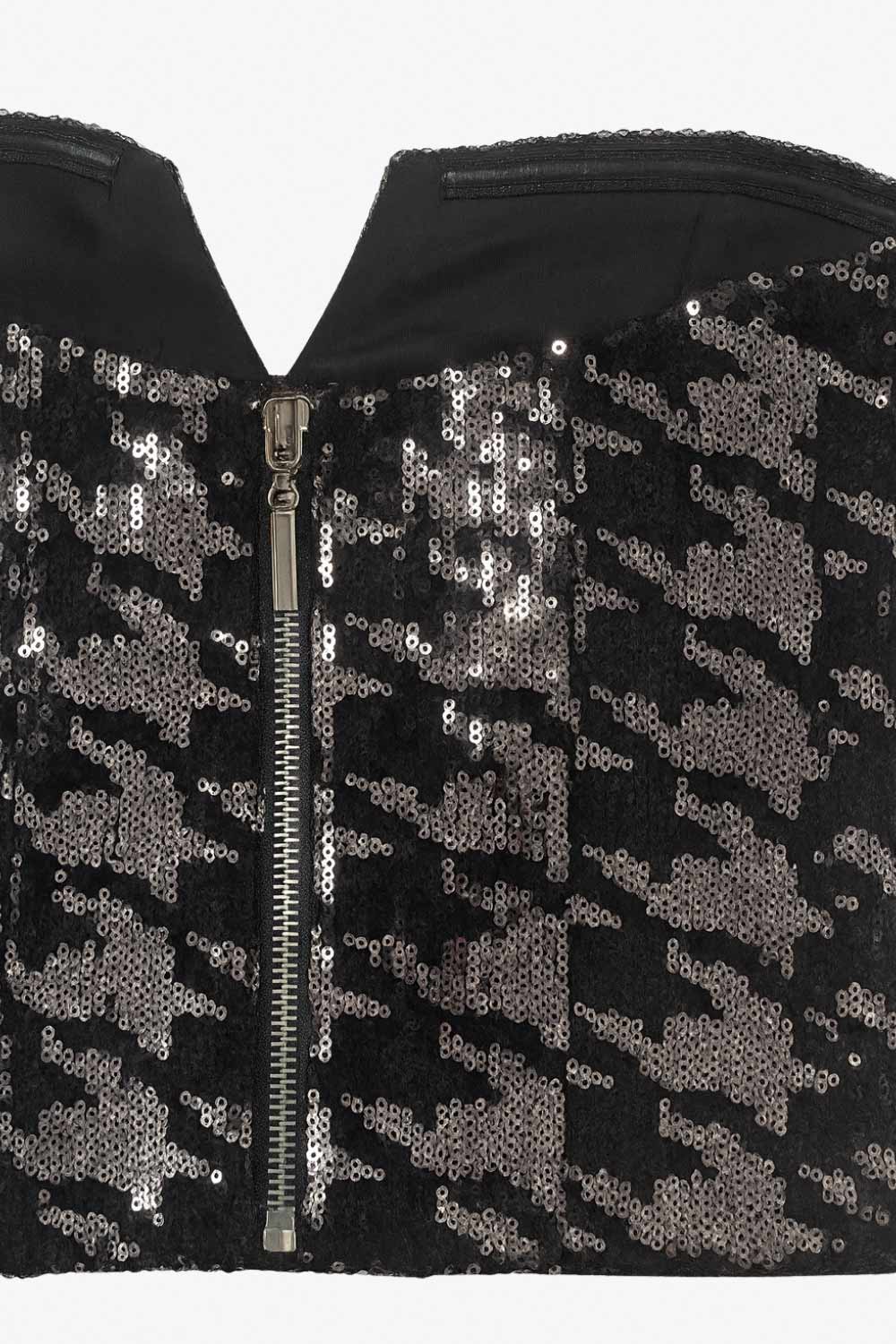 Crop top strapless de lentejuelas, estampado pata de gallo, escote corazón con detalle en v, cortes frontales y cierre posterior con cremallera visible en contraste.