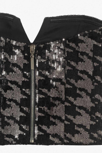 Crop top strapless de lentejuelas, estampado pata de gallo, escote corazón con detalle en v, cortes frontales y cierre posterior con cremallera visible en contraste.