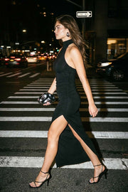 Vestido midi de fit ajustado, sin mangas y cuello alto halter. Detalle de plisados en costados, abertura lateral en bajo, cierre posterior con botón y ojal.