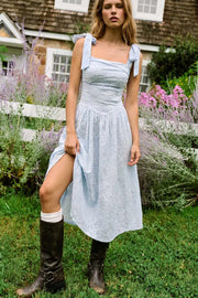 Vestido midi de bordado floral con perforado, tirantes con nudo amarrable, escote recto con cortes y plisados decorativos, corte en a, plisados en cintura con corte frontal en v y fruncido en espalda.
