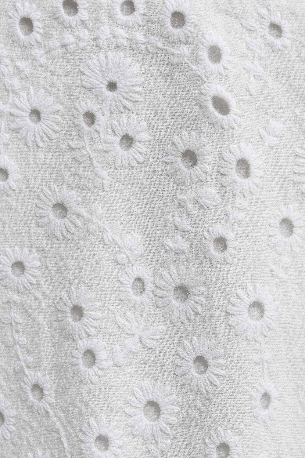 Vestido corto bordado de escote v con plisados frontales, corte en a, capas de olanes en bajo y tirantes con nudo amarrable. Cierre posterior con cremallera oculta y detalle de perforado en tejido.