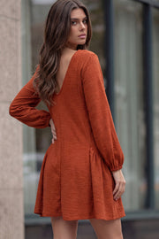 Vestido corto de fit fluido, escote v, manga 3/4 abullonada con rib elástico en puños y plisados decorativos laterales con elástico.