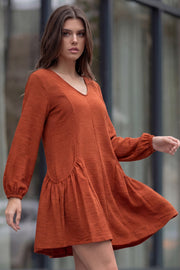 Vestido corto de fit fluido, escote v, manga 3/4 abullonada con rib elástico en puños y plisados decorativos laterales con elástico.