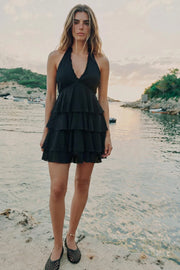 Vestido corto de cuello halter con nudo amarrable posterior, escote v con cortes y plisados decorativos, corte en a&nbsp; y capas de olanes en bajo. Escote en espalda y cierre posterior con cremallera oculta.