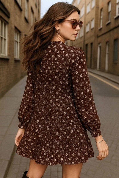 Vestido corto de estampado floral, fit fluido, manga larga con puño abotonado, escote v cruzado y plisado en cintura con olanes en bajo.