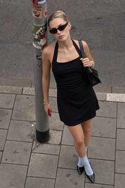 Vestido corto de fit ajustado, cuello halter con lazo amarrable posterior, escote recto, corte en a y plisados en costados.