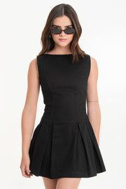 Vestido corto de fit ajustado, cuello barco, sin mangas, cortes frontales decorativos y bajo con tableado. Escote en espalda con lazo amarrable y cierre posterior con cremallera visible en contraste.