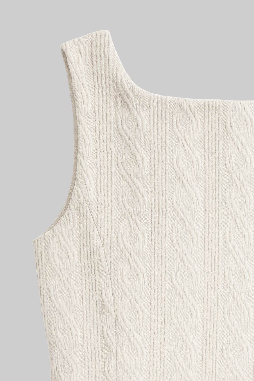 Vestido corto de cuello barco, sin mangas, pinzas frontales, escote en espalda y corte en a con olanes en bajo. Detalle de textura en tejido.