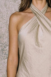Vestido largo de fit fluido, cuello halter cruzado con lazo amarrable posterior, escote en espalda y cierre posterior con cremallera oculta. Detalle de abertura lateral en bajo.