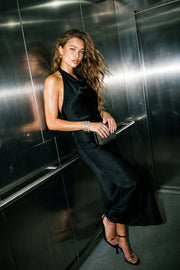Vestido largo satinado de fit fluido, cuello halter con lazo amarrable posterior, escote en espalda y frontal fluido.