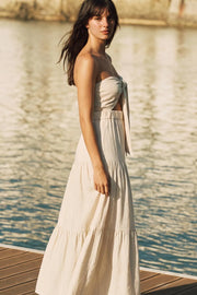 Vestido midi strapless de lino, escote corazón con nudo amarrable, cut out frontal, cintura elástica, detalle de capas de olanes en bajo y fruncido en espalda.